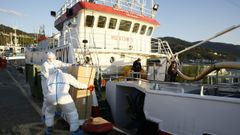 Protegidos con trajes especiales, empleados de Puerto de Celeiro ayudaron a la tripulaci�n que quedaba a bordo del Siempre Antares a descargar carnada este viernes por la tarde