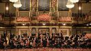 Imagen de la orquesta con el escenario engalanado con flores. 