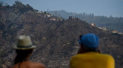 Dos personas observan la devastaci�n causada por el fuego en un monte de Babosas, en Madeira