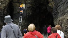 Visitantes de As Catedrais observan los trabajos de colocaci�n de carteles que advierten de las zonas peligrosas