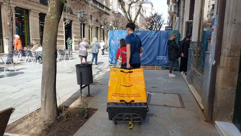 Un repartidor, con un carrito para hacer las entregas de paquetes en el casco viejo yendo a pie.