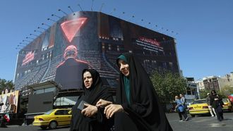 Dos mujeres iran�es caminan ante un mural que representa al primer ministro israel� en funciones, Benjamin Netanyahu