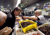 Una pescantina muestra percebes a un cliente en A Coru�a.