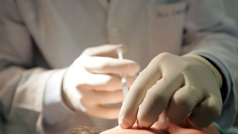 Un cirujano inyectando botox a una paciente 
