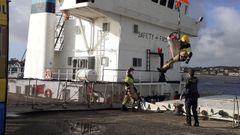 Dos bomberos y un guardia civil, en el momento de sacar al hombre de barco con la ayuda de una gr�a