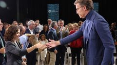 Feijoo ofrece su mano a Ayuso para que suba al estrado.