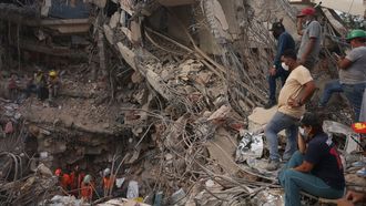 Un grupo de personas observa a los efectivos de rescate en el interior de un edificio colapsado en Caraballeda, en el estado de La Guaira