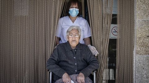 Encarna Enrquez, con su cuidadora Maria, en la puerta de la vivienda comunitaria de Lodoselo