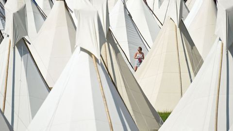Una visitante pasean entre las tiendas tipi instaladas en el festival de Glastonbury, en Somerset (Reino Unido)
