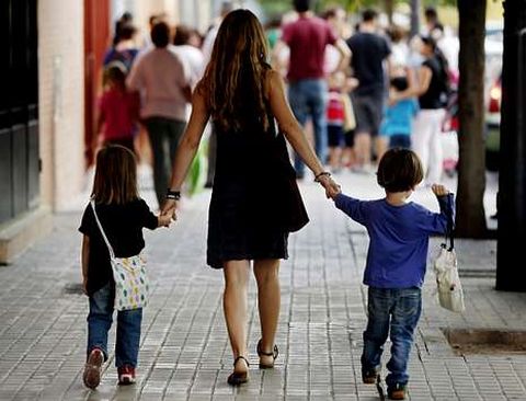 Una madre lleva a sus hijos pequeos al colegio el primer da de inicio de las clases.