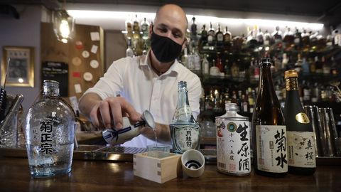 Un barman muestra diferentes botellas de sake, bebida tpica japonesa