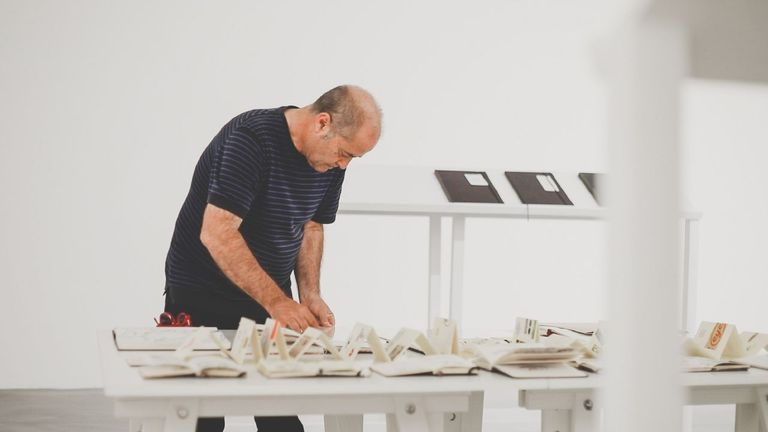 Pepe Barro colocando os seus cadernos nunha mostra anterior en Didac