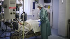 Un trabajador sanitario atiende a un paciente en una camilla de la uci  de la Cl�nica Universidad de Navarra, en Pamplona