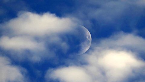 La media luna asomando entre las nubes al atardecer en Oviedo