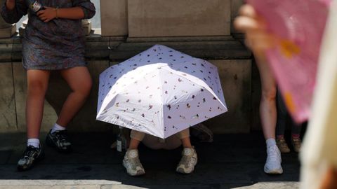 Un ni�o se protege del sol bajo un paraguas en Londres