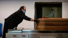 Un trabajador de una empresa funeraria de Gerona introduce un ata�d en un horno crematorio.