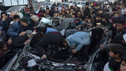 Palestinos registran un coche destruido por un bombardeo israel en Rafah.