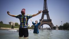 Dos turistas intentan refrescarse del calor en la fuente de Varsovia situada a los pies de la torre Eiffel.