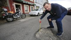 Manuel L�pez, delante del bar O Chuco de A Ponte, mostrando en el 2019 los baches