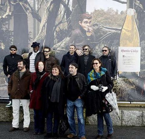 Los artistas posan ante un mural de la bodega.