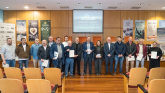 En el centro, Marta Villaverde, conselleira do Mar, con dirigentes del sector pesquero de Burela y armadores de pincheiros en el acto del 13 de marzo del 2026 con el que 24 barcos renuevan la ecoetiqueta Pescaenverde, expedida por la Universidade de Santiago.