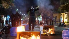 Manifestantes en Tirana, la capital de Albania, sobre contenedores ardiendo que colocan como barricadas
