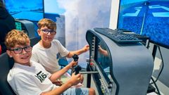 Escolares manejando uno de los simuladores de vuelo del Aula Newton de la Tecnópole