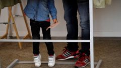 Un elector, con su hija, en una de las cabinas para elegir los votos, en Pola de Siero