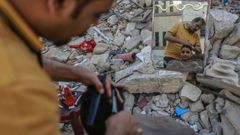 Un palestino corta el pelo a un ni�o entre las ruinas de un edificio en Gaza