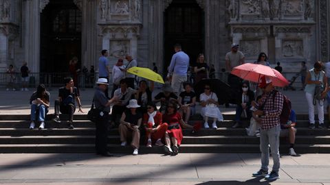 Varias personas se protegen del sol con paraguas durante una ola de calor junto a la catedral del Duomo, en Mil�n (Italia).