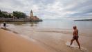 Un hombre camina por la playa de San Lorenzo de Gij�n, en un d�a nublado del verano del a�o pasado
