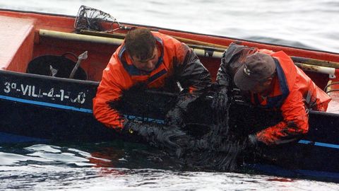 Pescadores recogiendo el chapapote con sus manos