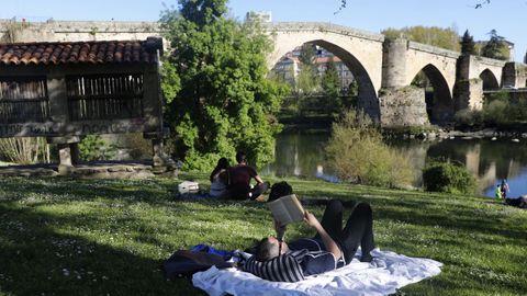 Un hombre reposa junto al Puente Viejo de Ourense este lunes.