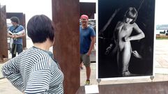 Dos espectadores ante obras de la serie �G�nesis�, de Salgado, en la explanada del Na�tico gijon�s