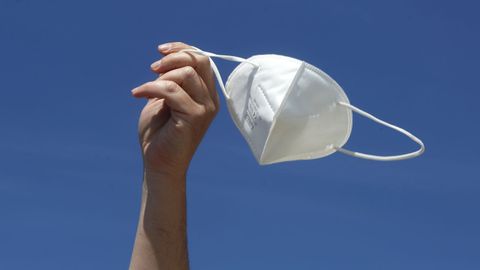 Un mozo sost�n unha m�scarilla o aire o d�a que cambia a normativa do seu uso en esteriores