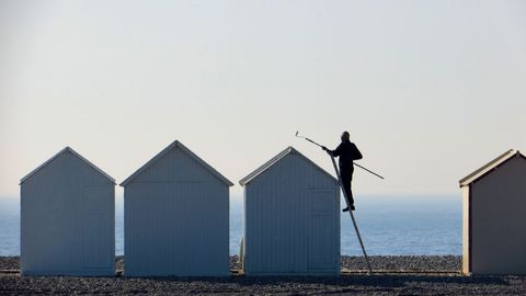 Un hombre pinta el techo de una caseta de playa en Cayeaux-sur-Mer, en Francia