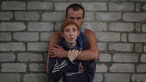 Una pareja observan el trabajo de los equipos de rescate en espera de noticias de familiares atrapados bajo los escombros del edificio atacado en Chasiv Yar, en Donetsk