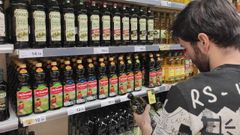 Un cliente de un supermercado compara precios de una botella de aceite.