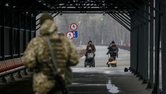 Dos personas cruzan la l�nea de contacto que seprara la zona prorrusa de la ucraniana en Lugansk.