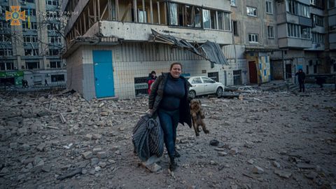 Una mujer con un perro evacua de un edificio residencial daado por los bombardeos, mientras contina el ataque de Rusia a Ucrania, en Kiev