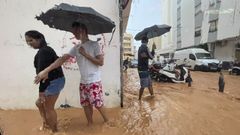 Varias personas caminan por las calles inundadas de la ciudad de Ibiza.
