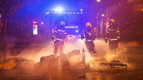 Miembros del cuerpo de bomberos apagan las papeleras quemadas en Logro�o 