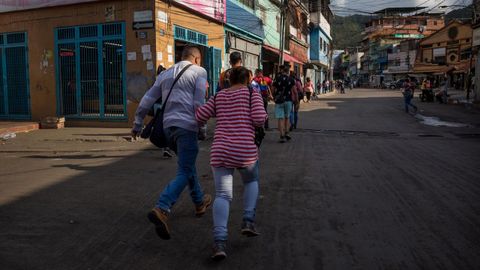 Un grupo de personas corren para refugiarse durante un tiroteo en el conflictivo barrio caraque�o de La Vega