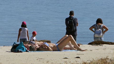 Gente tomando el sol ayer en O Carreir�n, en la Illa de Arousa
