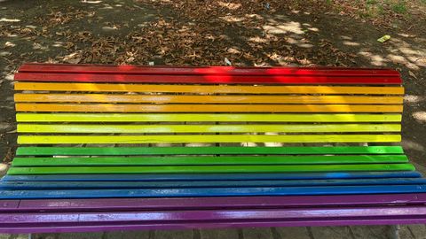Banco pintado con la bandera arcoiris, en Mieres