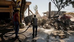 Un hombre ayuda a limpiar las calles de Maaysrah tras un bombardeo israel.