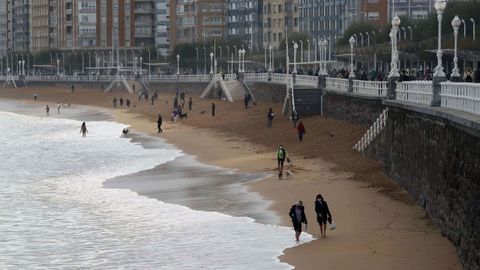 Varias personas caminan por la playa de San Lorenzo de Gijn