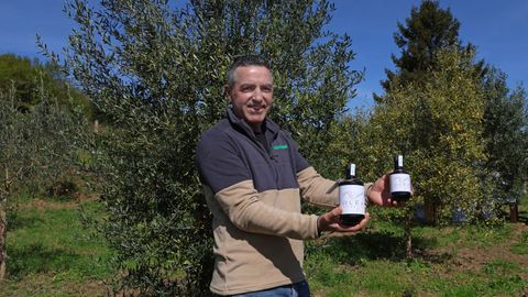 Gonzalo Garc�a posa en su olivar con botellas de la primera producci�n de Olea Atl�ntica.
