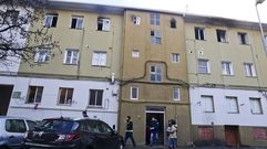 Polic�as saliendo del edificio, ante la mirada de periodistas la puerta y de vecinos en las ventanas.