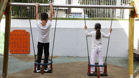 Dos niños juegan en unos columpios de un parque infantil en A Coruña.